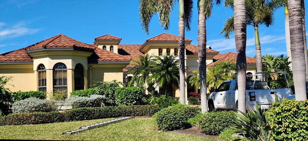 Yellow home with Mediterranean roof with a white truck and palm trees in the front yard