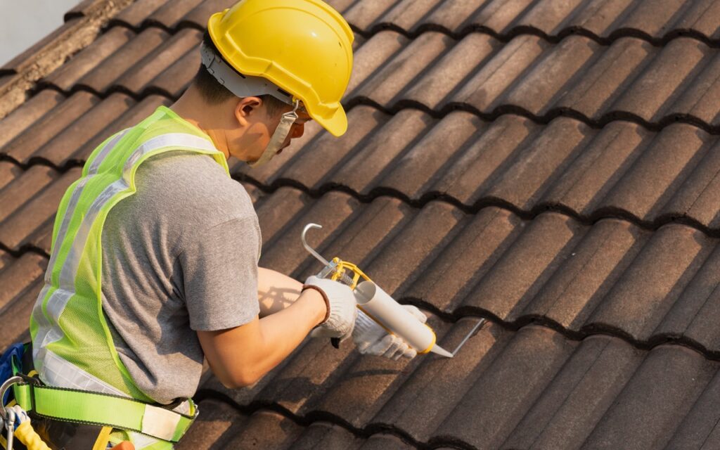 A roofing repairman resealing a cracked clay roof